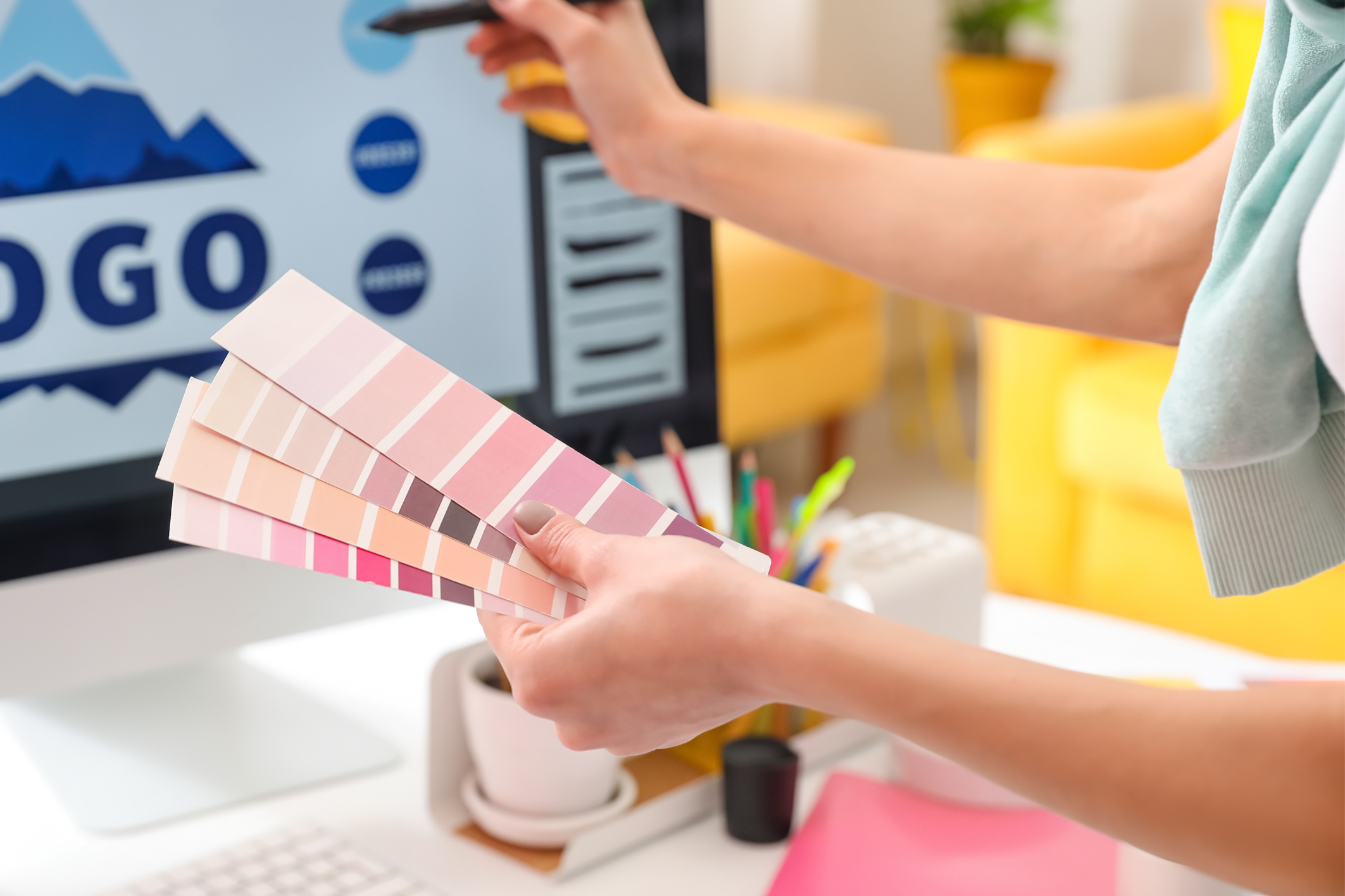 An Image of a woman holding up color swatches to pair with a company logo