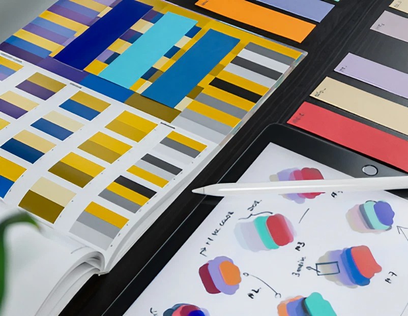 A variety of colour palettes on a desk with a tablet displaying different colour combinations.