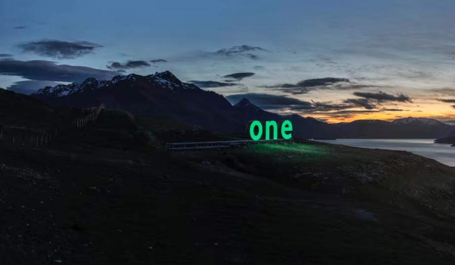 The word ‘one’ glowing over a night-time New Zealand landscape.