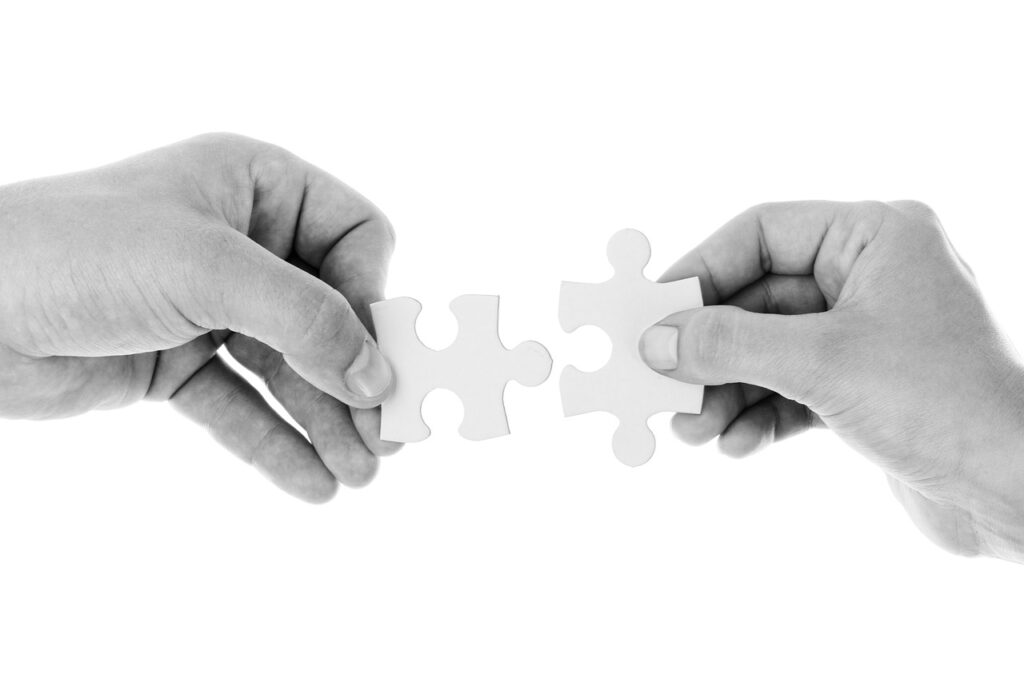 Two hands connecting puzzle pieces together.